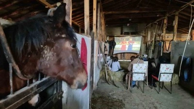 Çocukların at çiftliğinde saman balyaları üstünde sinema keyfi